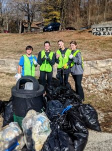 Students with green vests cleaning outdoors