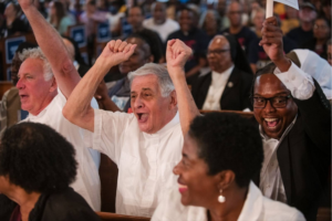 Elderly man in white shirt with hands raised